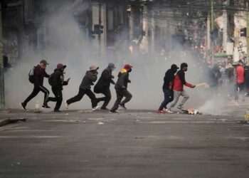Demonstrators run across a street during an anti-government protest in La Paz, Bolivia, Monday, May 18, 2026. (AP Photo/Freddy Barragan)