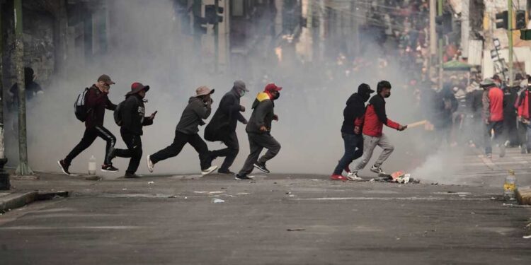 Demonstrators run across a street during an anti-government protest in La Paz, Bolivia, Monday, May 18, 2026. (AP Photo/Freddy Barragan)