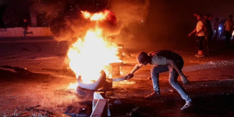 Halep ile Türkiye arasındaki otoyolda bir eylemci, Suriye'deki yakıt fiyatı artışını protesto etmek amacıyla lastik yakıyor; Halep, Suriye, 13 Eylül 2026. REUTERS/Mahmoud Hassano